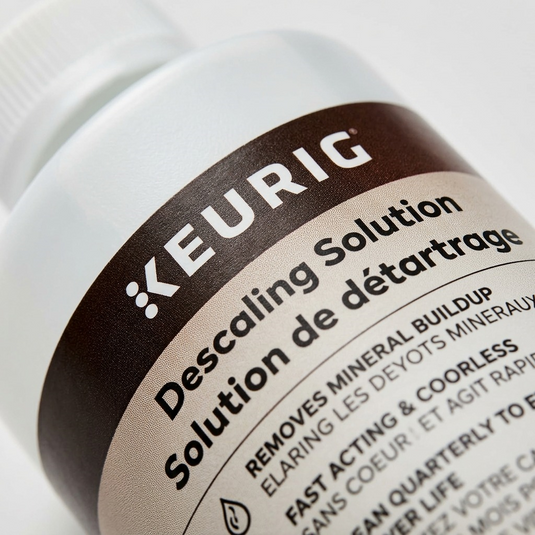 An extreme macro photograph of the textured Keurig logo and fine print on the solution bottle's matte label.