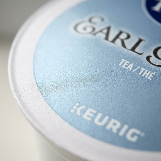 Extreme close-up of a K-Cup's lid texture, showing the embossed 'KEURIG' name.