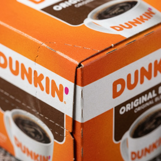 A macro photo of Dunkin' K-Cup box edge, focusing on cardboard texture and printed graphics.