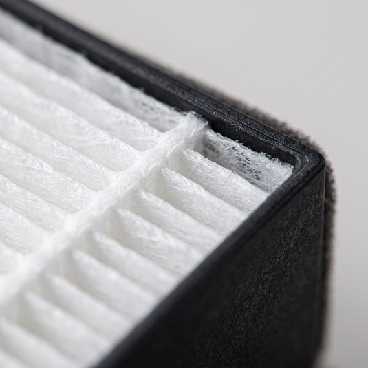 A macro photograph detail of the SHARP FZP30SFU True HEPA replacement filter, showing the tight white pleated media texture and its interface with the dark frame.